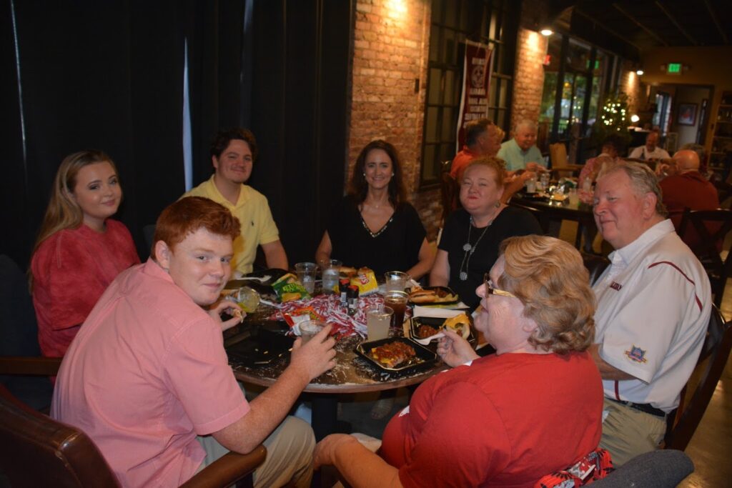 Group of people sitting at table in dim light room.