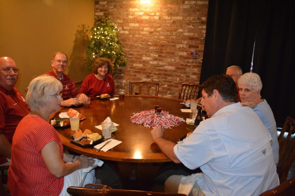 Group of people sitting at table in dim light room.
