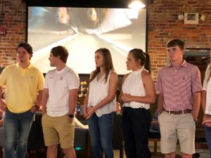 Group of people standing in front of white screen.