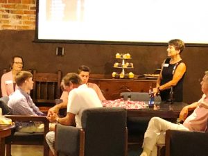 group of people sitting in room with white screen in background.