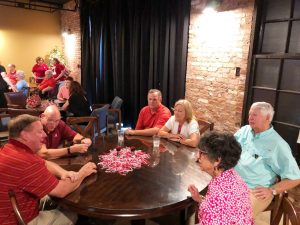 Group of people sitting at table with black curtain in background.