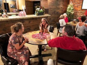 Group of people sitting at table with bar in background.