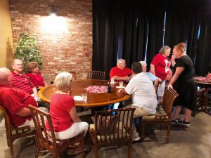 Group of people sitting at table in front of brick wall.