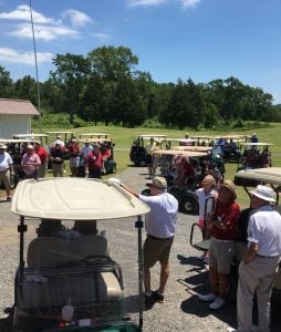 People standing by Golf Cart outside.
