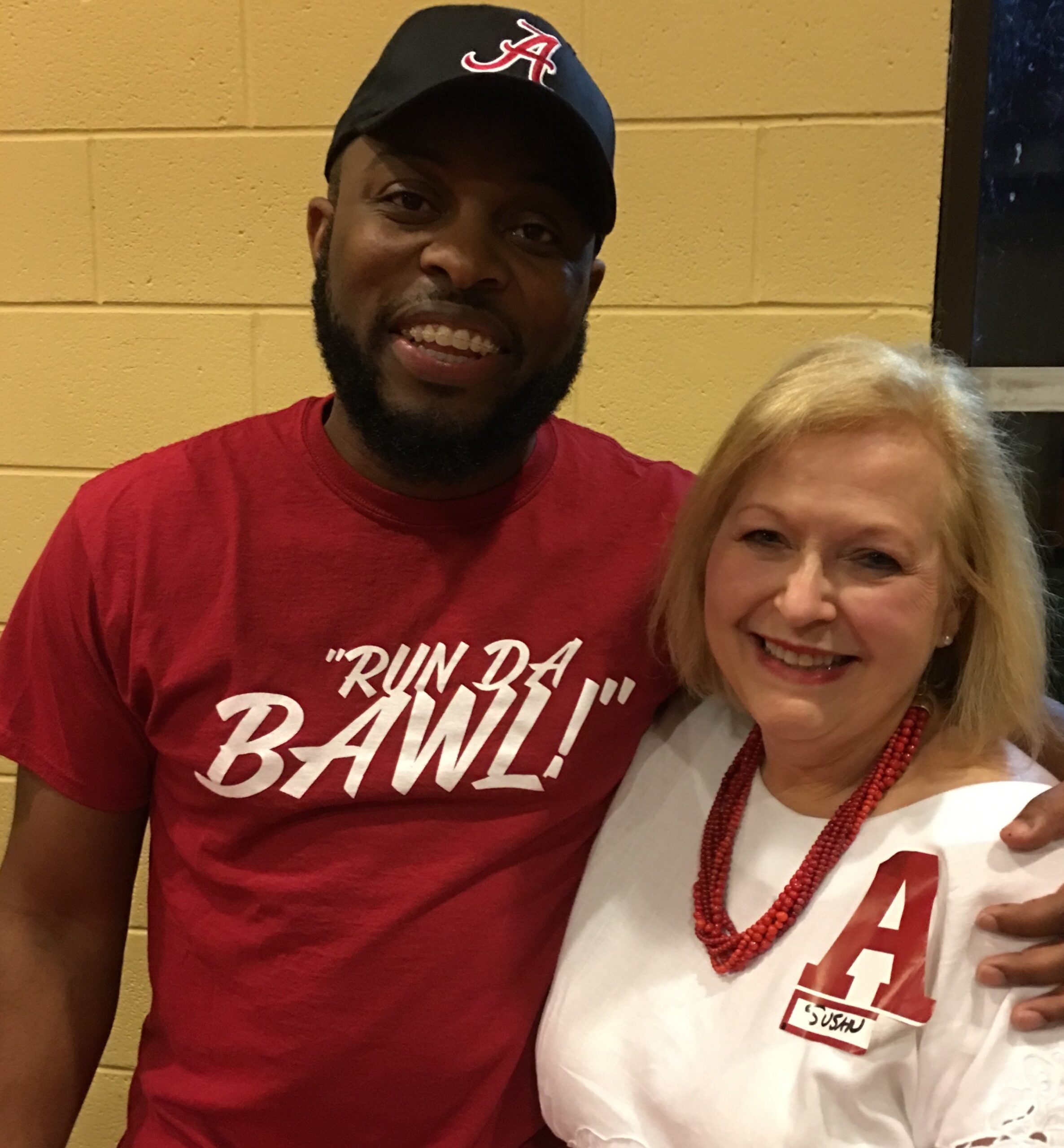 Susan Krell and man in red shirt standing in front of yellow wall