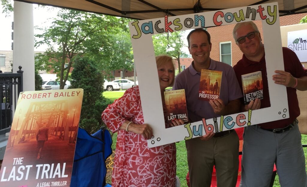 Man and Women looking throught card picture frame outside.