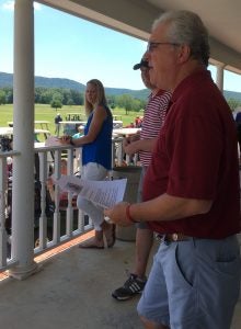 Two men and a lady standing on porch outside.