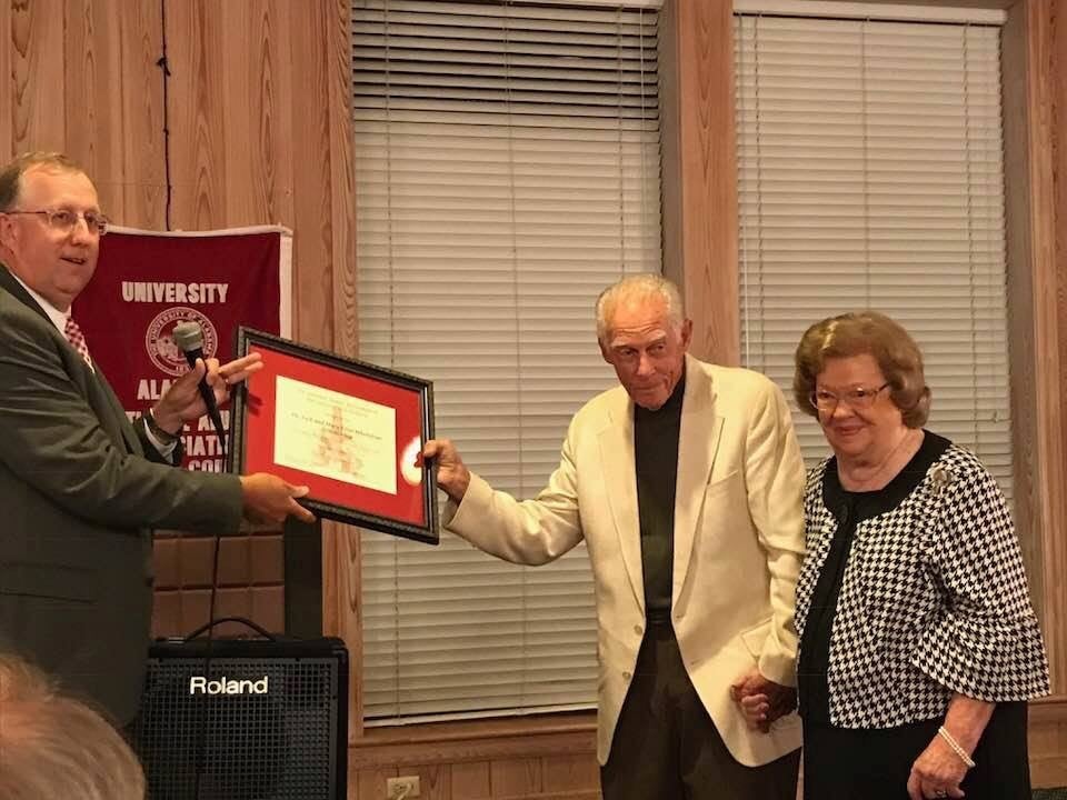 Three people standing in front of window with plaque.