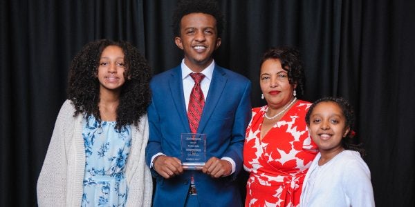 UA student with his family, he is holding an Alumni Student award