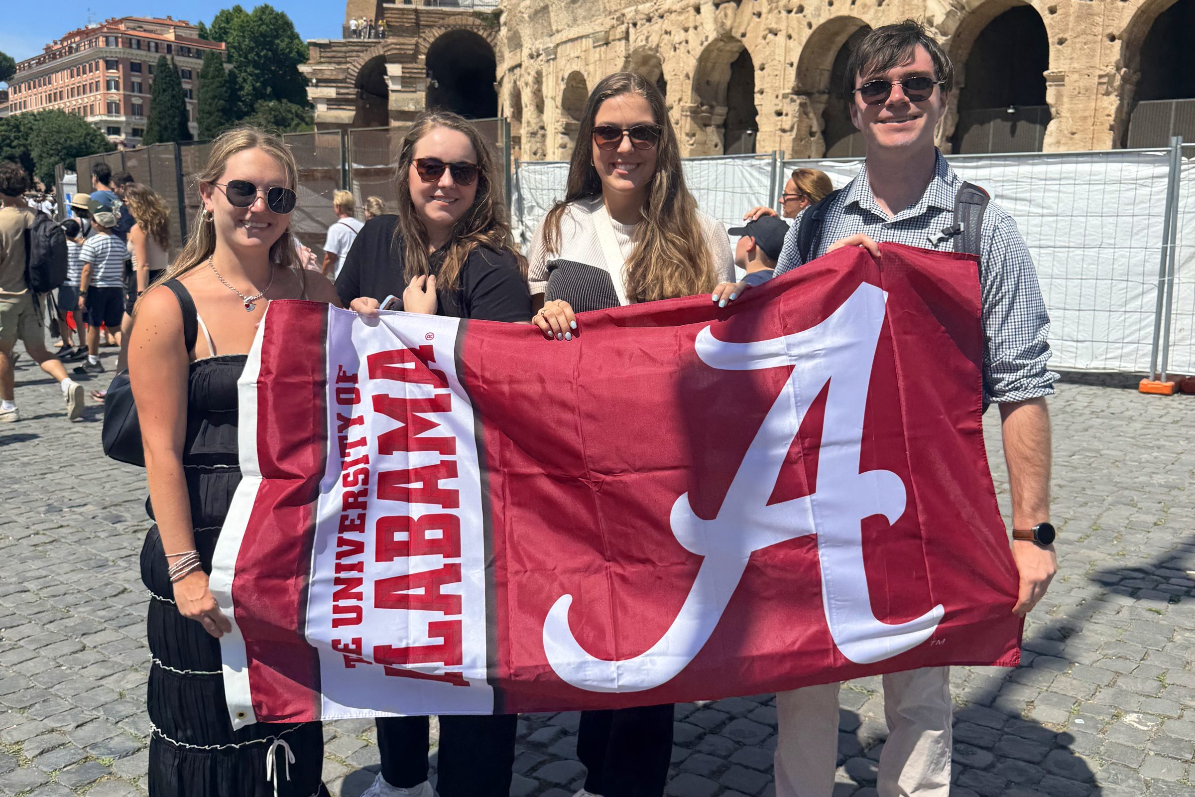 A group of UA alumni holding a large flag emblazoned with a script A