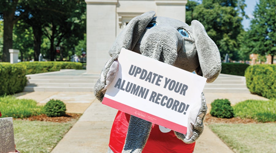 Big Al holding a poster reading UPDATE YOUR ALUMNI RECORD