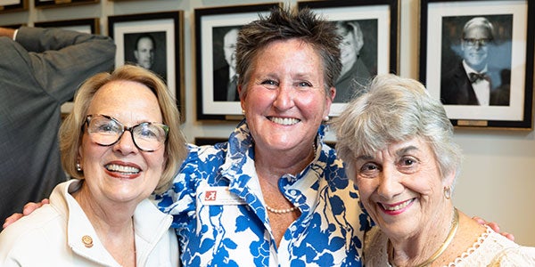 three past presidents of the NAA standing in front of photos of other past presidents